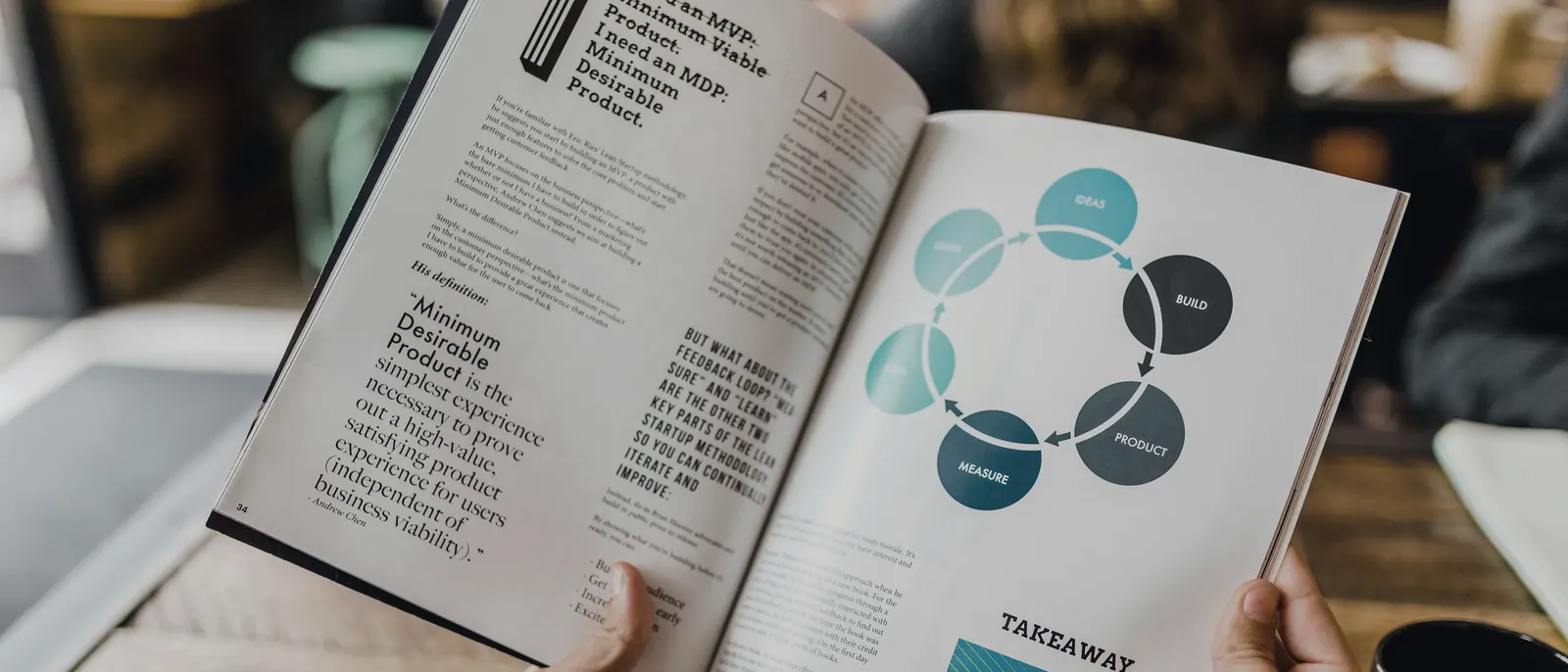 Mãos folheando um livro aberto sobre método de gestão, com um diagrama de ciclo desenhado na página